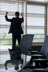 Jubelnder Geschäftsmann im Büro am Fenster - KFF000143