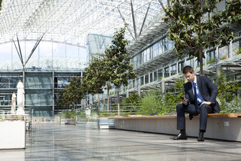 Businessman with cell phone in courtyard stock photo