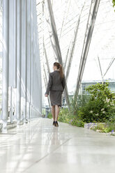 Businesswoman walking in modern courtyard - KFF000144