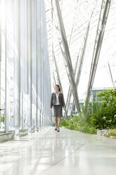 Businesswoman walking in modern courtyard - KFF000161