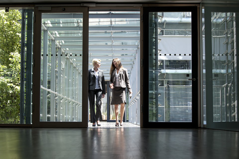 Zwei Geschäftsfrauen unterhalten sich in einem Bürogebäude, lizenzfreies Stockfoto
