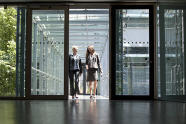 Two businesswomen talking in office building - KFF000128