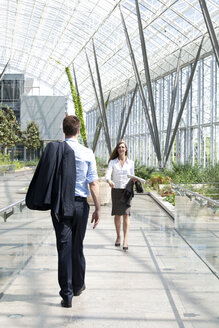 Geschäftsmann und Geschäftsfrau gehen in einem modernen Bürogebäude spazieren - KFF000135