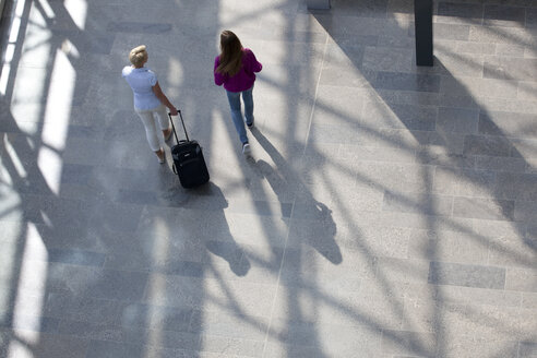 Woman walking with rolling suitcase accompanied by friend - KFF000149