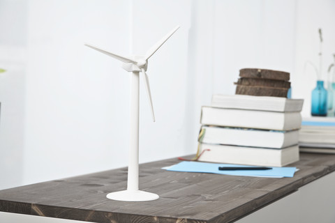 Deutschland, Nordrhein-Westfalen, Moderne Windmühle und Bücherstapel auf Tisch, lizenzfreies Stockfoto