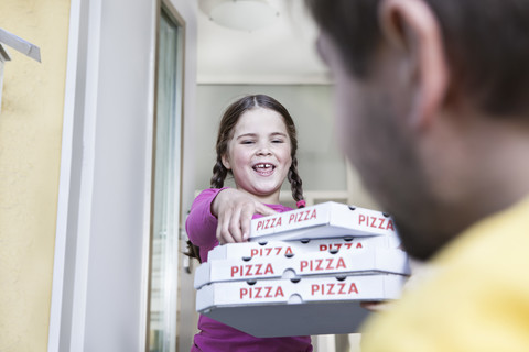 Deutschland, Nordrhein-Westfalen, Köln, Mädchen nimmt Pizzakartons vom Pizzaboten, lächelnd, lizenzfreies Stockfoto