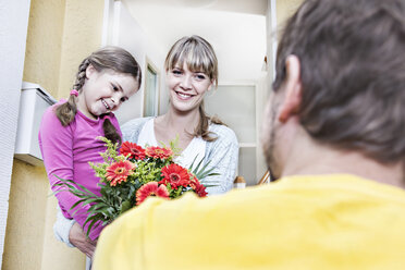 Deutschland, Nordrhein-Westfalen, Köln, Mutter und Tochter nehmen Blumen vom Postboten entgegen, lächelnd - FMKYF000511