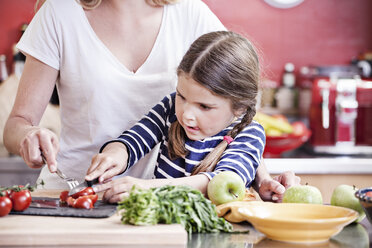 Germany, North Rhine Westphalia, Cologne, Mother and daughter cutting vegetables - FMKYF000471