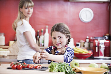 Germany, North Rhine Westphalia, Cologne, Mother and daughter cutting vegetables - FMKYF000470