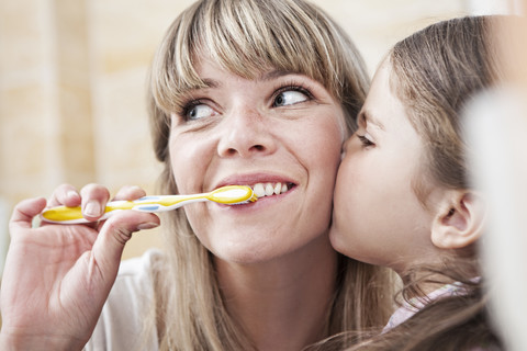 Deutschland, Nordrhein-Westfalen, Köln, Mutter putzt Zähne, während Tochter küsst, Nahaufnahme, lizenzfreies Stockfoto