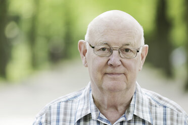 Deutschland, Nordrhein-Westfalen, Köln, Porträt eines älteren Mannes mit Brille im Park, lächelnd - JAT000114