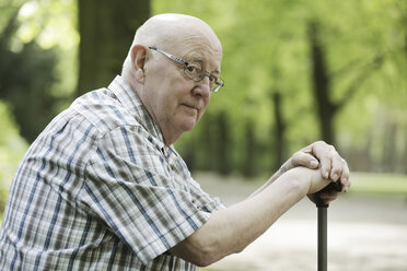 Germany, North Rhine Westphalia, Cologne, Portrait of senior man sitting on bench with walking stick in park - JAT000119