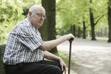 Germany, North Rhine Westphalia, Cologne, Senior man sitting on bench with walking stick in park - JAT000120
