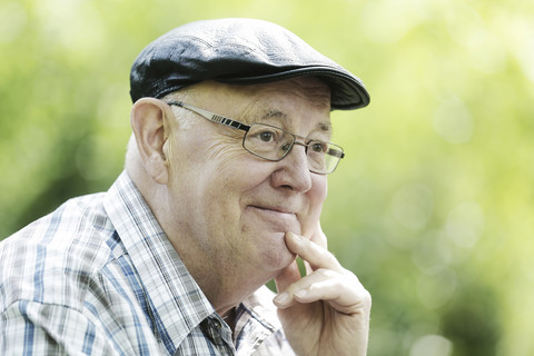 Deutschland, Nordrhein-Westfalen, Köln, älterer Mann mit Mütze und Brille im Park, Nahaufnahme, lizenzfreies Stockfoto