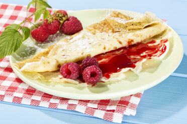 Pancakes with raspberry-jam and fresh raspberries on table - MAEF007022