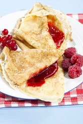 Pancakes with raspberry-jam, raspberries and fresh lowbush cranberries in plate - MAEF007012