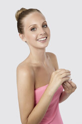 Porträt einer jungen Frau, die lächelnd eine Creme ins Gesicht hält - GDF000120