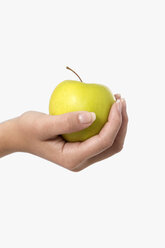 Mensch hält grünen Apfel vor weißem Hintergrund, Nahaufnahme - GDF000126