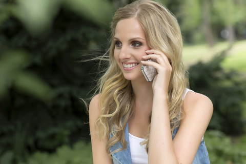 Deutschland, Oberhausen, Junge Frau telefoniert mit Handy, lächelnd, lizenzfreies Stockfoto