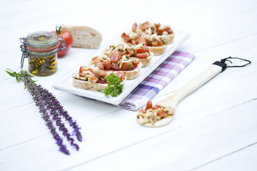 Teller mit Bruschetta mit Tomaten, weißen Shimeji-Pilzen, Kräutern und Olivenöl auf Holztisch, Nahaufnahme - MAEF007042