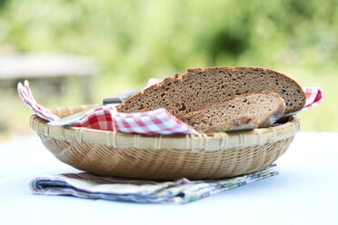 Korb mit Roggenbrot mit Serviette auf Holztisch, Nahaufnahme - MAEF007104