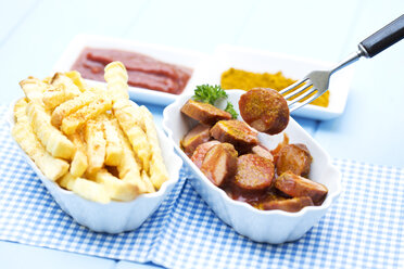 Schüssel mit Würstchen mit Pommes frites, Currywurst und Ketchup auf Holztisch, Nahaufnahme - MAEF007038