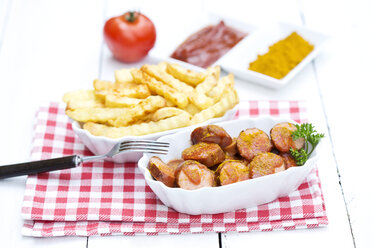 Schüssel mit Würstchen mit Pommes frites, Currywurst und Ketchup auf Holztisch, Nahaufnahme - MAEF007040