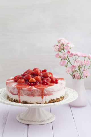 Erdbeerkäsekuchen mit frischen Erdbeeren und roten Johannisbeeren auf Holztisch, Nahaufnahme, lizenzfreies Stockfoto
