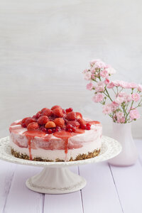 Erdbeerkäsekuchen mit frischen Erdbeeren und roten Johannisbeeren auf Holztisch, Nahaufnahme - ECF000293