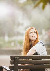 Germany, Berlin,Young woman sitting on bench and looking away - ZMF000012