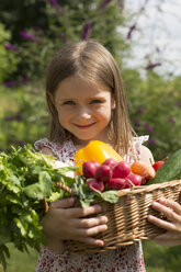 Deutschland, Bayern, Porträt eines lächelnden Mädchens mit einem Korb voller Gemüse - SARF000074