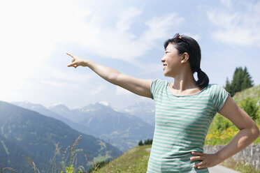 Österreich, Junge Frau zeigt auf Berghügel - FLF000332