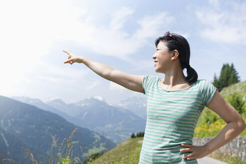 Austria, Young woman pointing at mountain hill - FLF000332