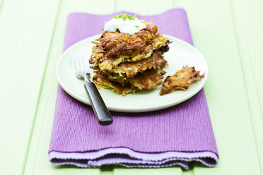 Plate of fried mashed potatoes with fork on wooden table, close up - MAEF007101