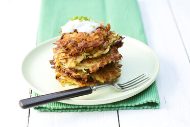 Plate of fried mashed potatoes with fork on wooden table, close up - MAEF007099