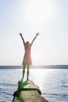 Germany, Bavaria, Mature woman standing with arms up at Lake Stamberg - TCF003523