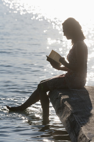 Deutschland, Bayern, Reife Frau liest Buch am Stamberger See, lizenzfreies Stockfoto