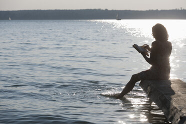 Deutschland, Bayern, Reife Frau liest Buch am Stamberger See - TCF003526