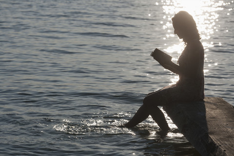 Deutschland, Bayern, Reife Frau liest Buch am Stamberger See, lizenzfreies Stockfoto