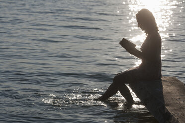 Deutschland, Bayern, Reife Frau liest Buch am Stamberger See - TCF003548