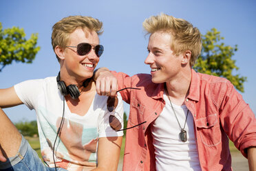 Germany, two friends listening to music with headphones - GDF000158