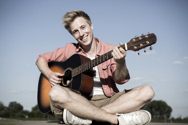 Deutschland, Junger Mann spielt Gitarre im Park - GDF000179