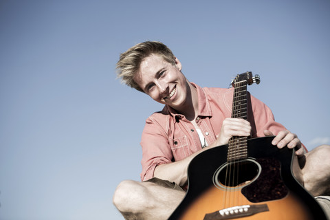 Deutschland, Junger Mann mit Gitarre, lächelnd, lizenzfreies Stockfoto