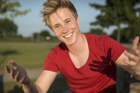 Germany, Young man sitting in park, gesturing stock photo