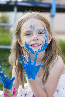 Deutschland, Bayern, Porträt eines mit Fingerfarben spielenden Mädchens, lächelnd - SARF000085