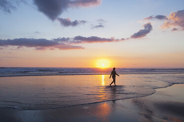 New Zealand, View of mature woman walking along beach - GW002352