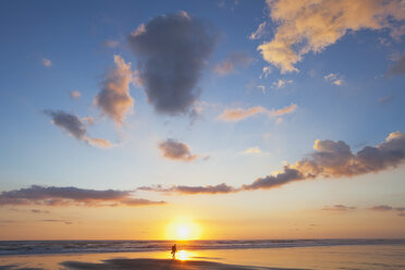 Neuseeland, Blick auf einen Mann mit Rucksack, der bei Sonnenuntergang am Strand entlang läuft - GWF002355