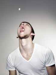 Young man playing with popcorns - STKF000315