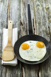 Fried eggs in pan with wooden spoon on napkin - OD000291