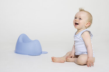 Baby boy sitting with chamber pot, smiling - MUF001360